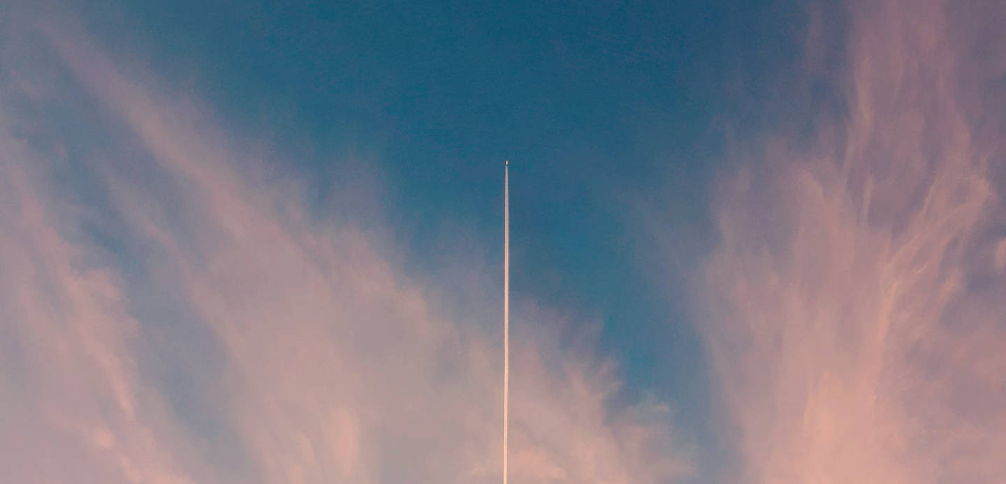 Scia di aereo nel cielo con sfumature rosa al tramonto